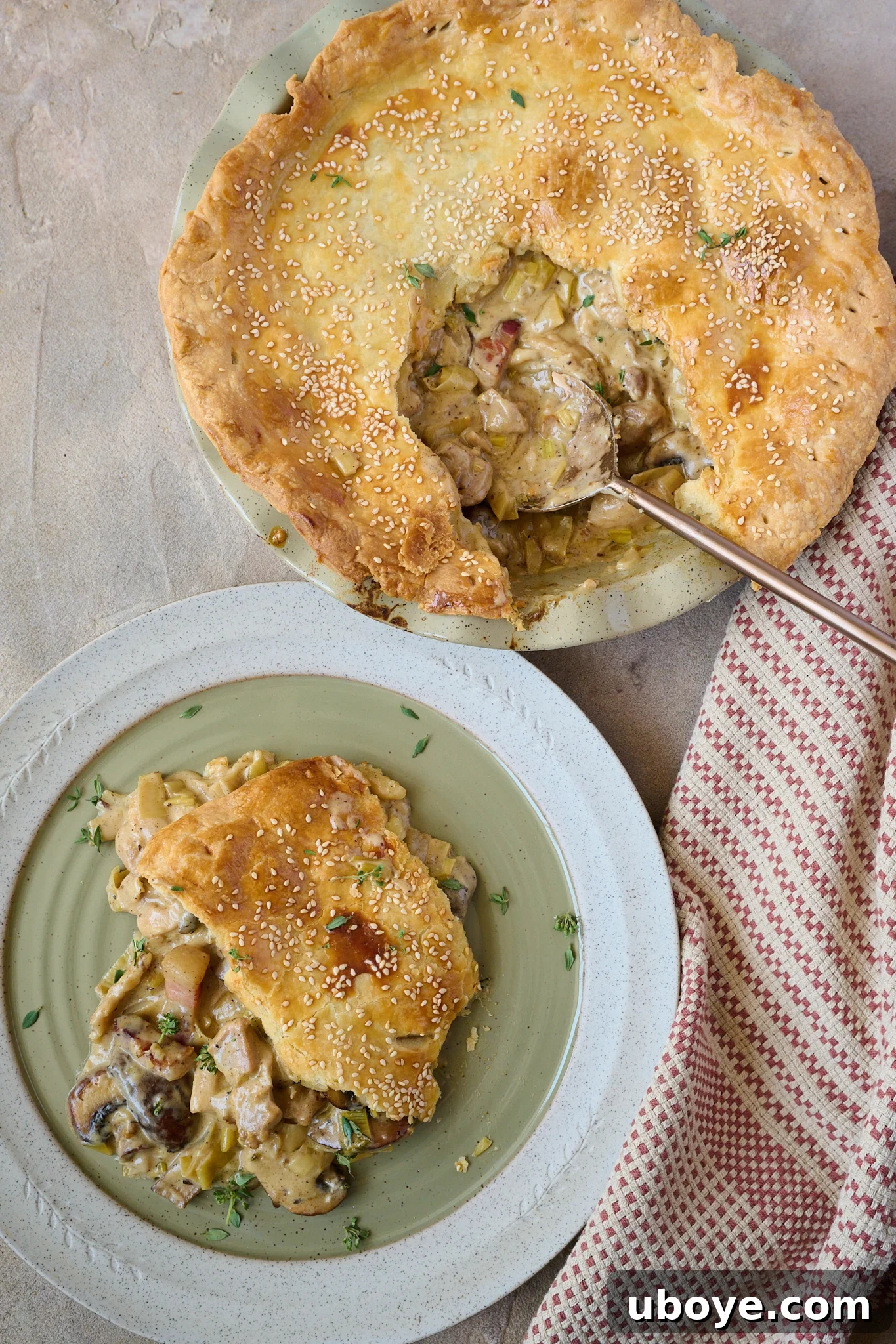 Hearty Chicken, Mushroom and Bacon Pot Pie 12 Creamy Chicken, Mushroom & Bacon Pot Pie is in green pie dish with a slice taken out of the middle and gold spoon sitting out of side. There is a green plate to the side of the pie with a slice of the pie on it.