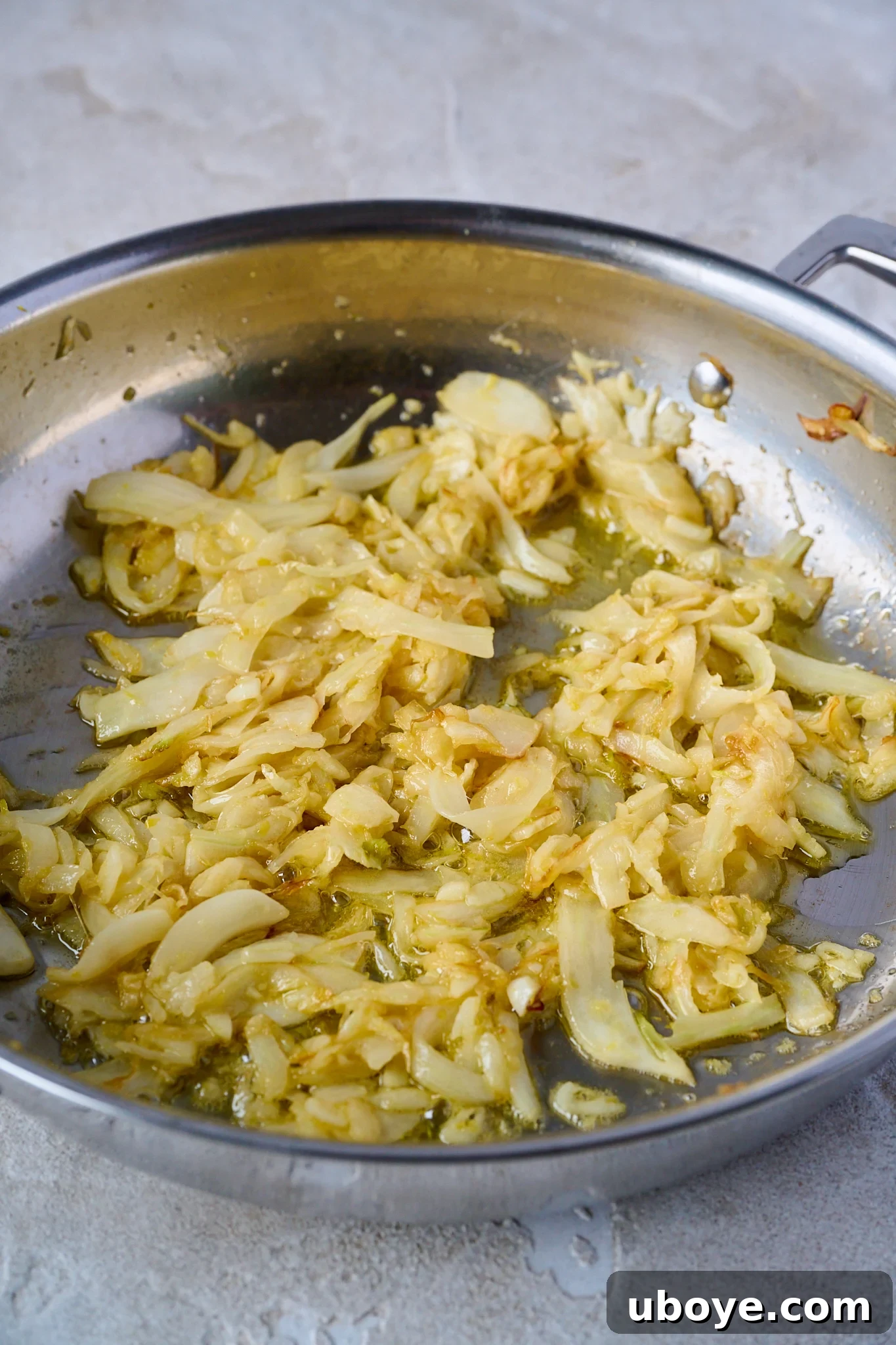 Thinly sliced fennel caramelizing in butter and olive oil in a large stainless steel pan.