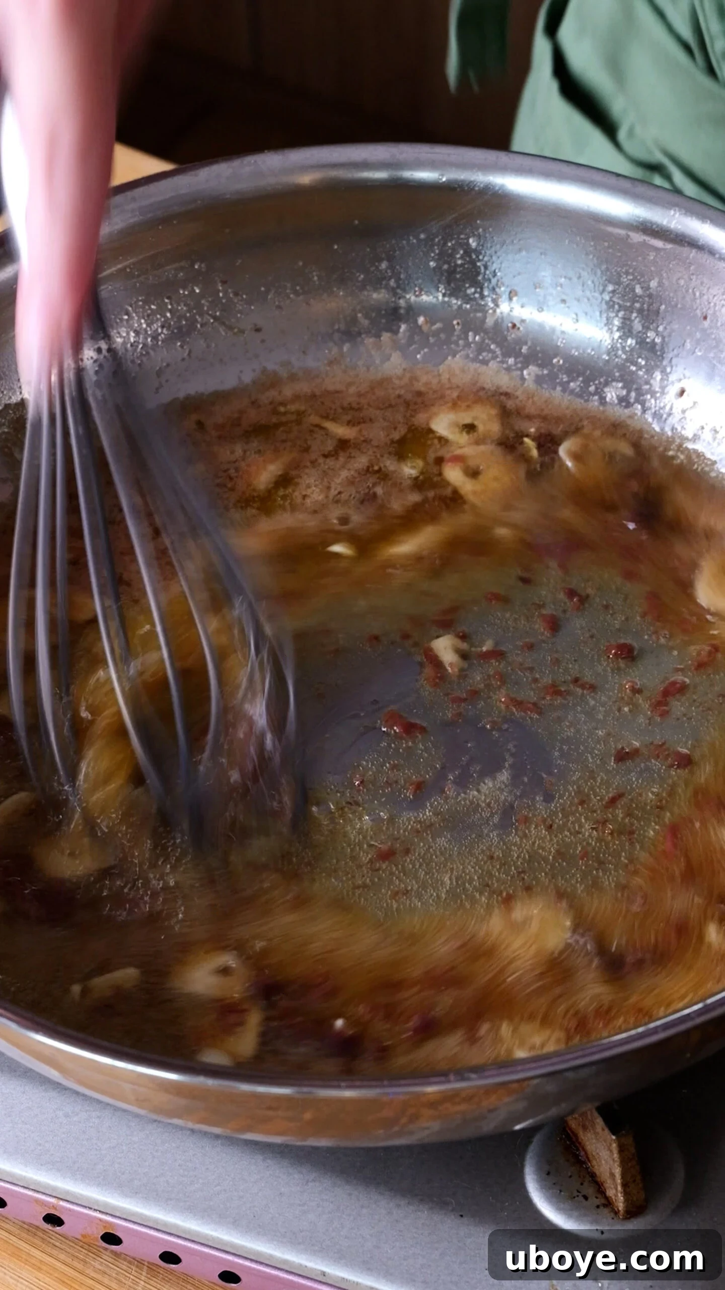 Decadent 10-Minute Anchovy Butter Pasta 6 A whisk vigorously mixes anchovy butter sauce in a large stainless steel pan, showing the anchovies melting into the butter.