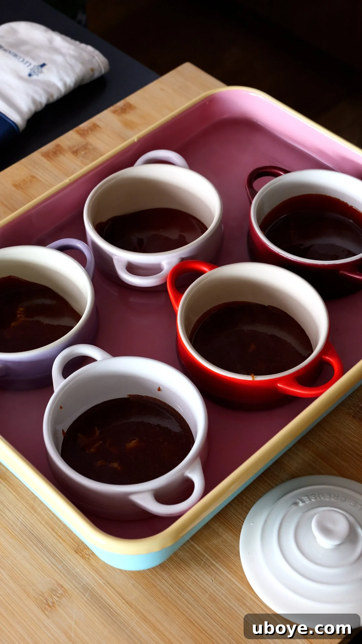 Classic Spanish Flan Recipe: Smooth Caramel Custard You’ll Love 6 five ramekins are in large pink baking tray and have been filled with caramel